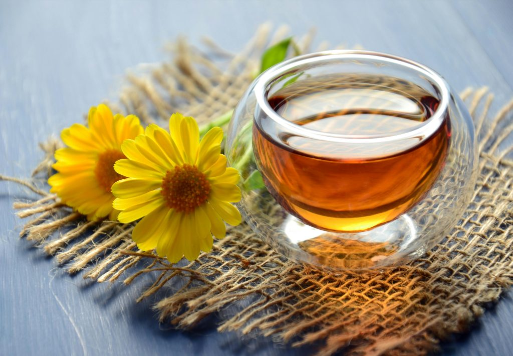 pexels-photo-1638280-1638280 Glass cup of herbal tea with yellow flowers on a textured background.