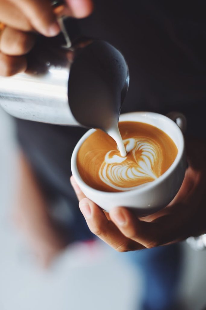 pexels-photo-302896 Close-up of barista pouring milk to create stunning latte art in a coffee shop setting.